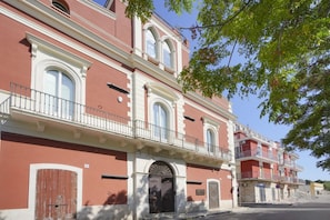 A multi-story building with a red facade, white trim, and balconies.