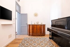 Une pièce avec un meuble en bois, un piano, un tapis à motifs et une horloge murale.