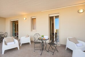 Ein Balkon mit weißen Stühlen, einem Tisch mit einer Pflanze und einem Schild.