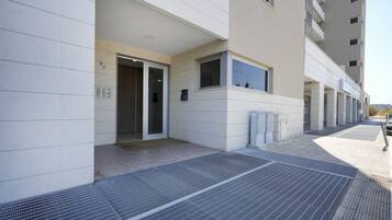 A modern building with a clean, white facade, a covered entrance, and a visible elevator.