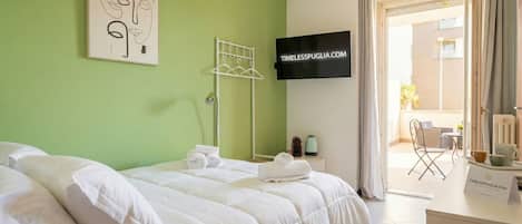 Habitación de hotel con cama, televisor, escritorio y vistas al exterior.