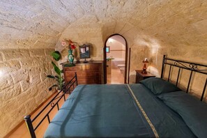 A bedroom with a bed, dresser, mirror, and a small table with a lamp.