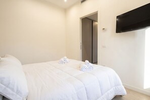 A hotel room with a bed, a TV mounted on the wall, and a door leading to a closet. - Suite Calle - City Center Modern Apartment+Balcony (Bari)