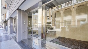 A modern building facade with large glass windows and a stone archway. - Calle Suite - Modern Apartment with Balcony (Bari)
