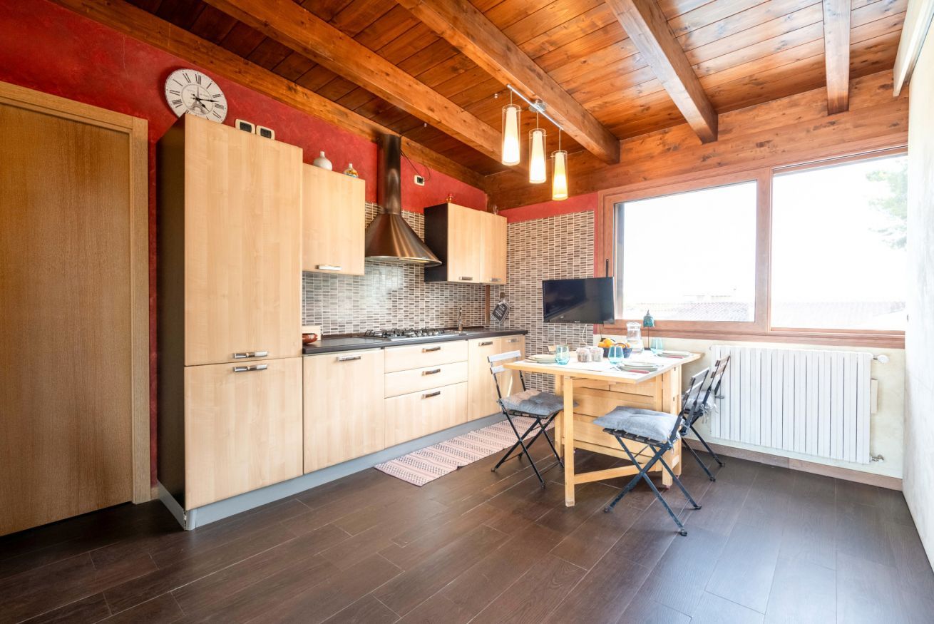 Une cuisine avec des meubles de rangement en bois, une cuisinière et un coin repas comprenant une table et des chaises.