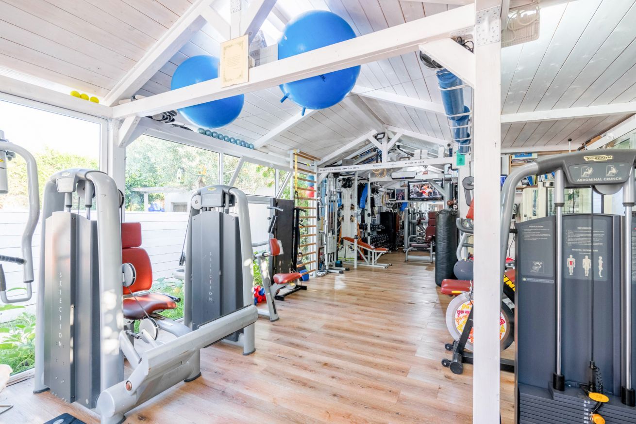 Una palestra con diverse macchine per esercizi, un pavimento in legno e grandi palloni da ginnastica blu.