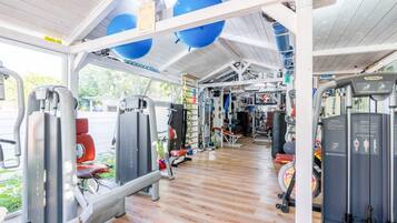 Una palestra con diverse macchine per esercizi, un pavimento in legno e grandi palloni da ginnastica blu.