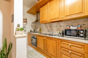 A kitchen with wooden cabinets, a microwave, and a sink.