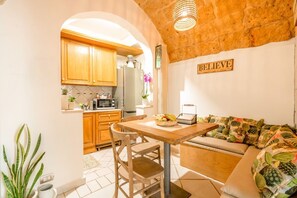 A cozy kitchen with wooden cabinets, a dining table, and a sofa with a 'BELIEVE' sign.
