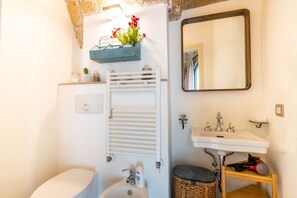 A bathroom with a toilet, sink, towel rack, and a mirror.