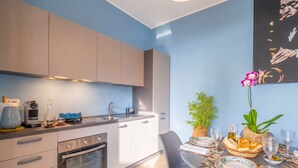 A modern kitchen with a built-in oven, a dining table set with plates, glasses, and a centerpiece. - Moonlight - Jacuzzi Suite (Bari)