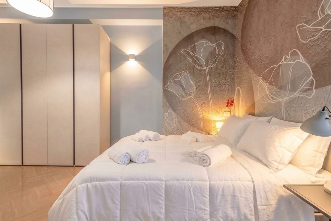 Un dormitorio con cama, luz empotrada en la pared y decoración floral.