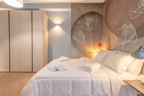 A bedroom with a bed, a wall-mounted light, and a decorative wall with floral patterns.