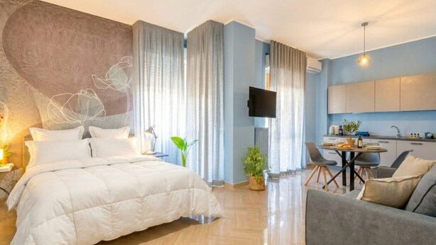 A modern hotel room with a bed, a TV, a dining area, and a kitchen. - Moonlight - Jacuzzi Suite (Bari)