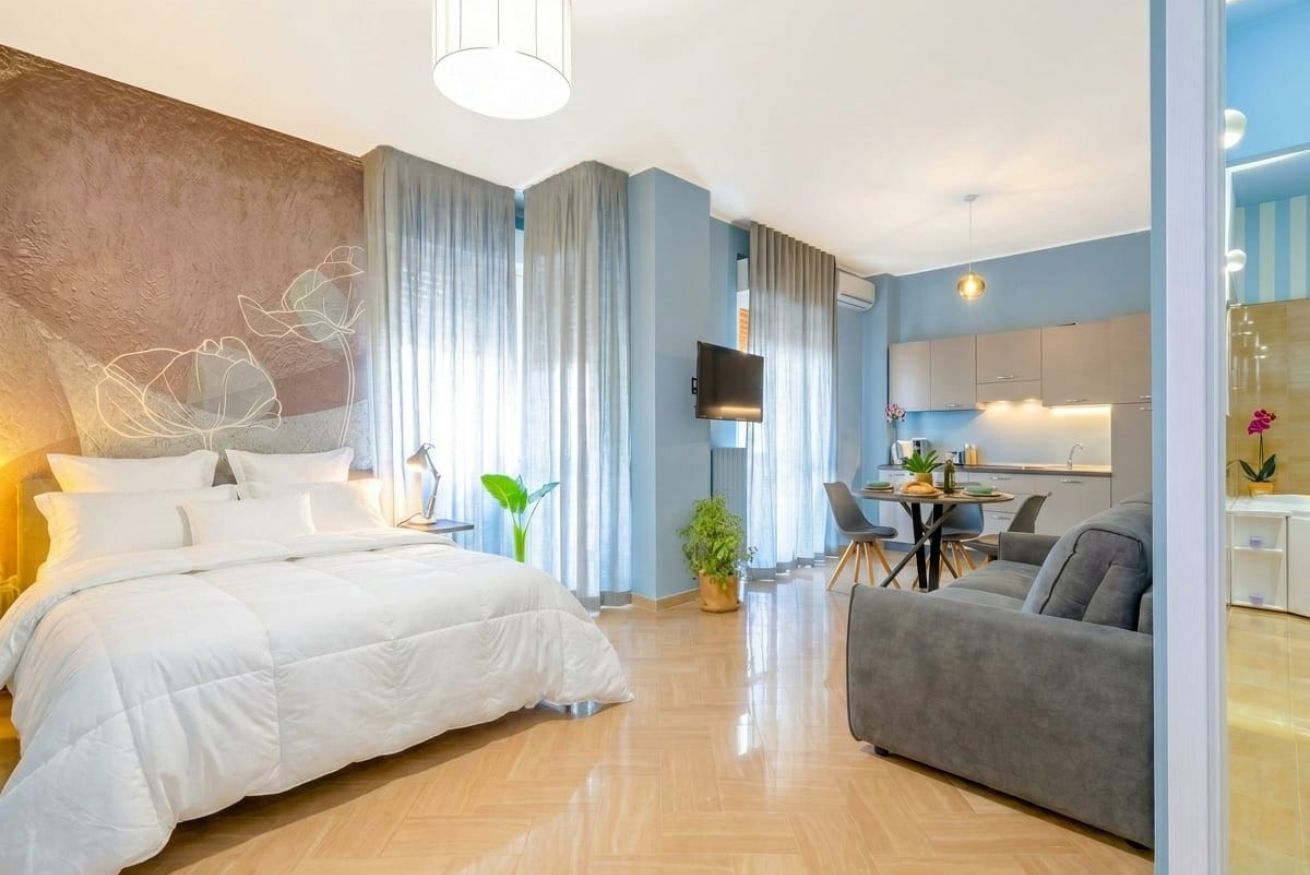 Ein modernes Hotelzimmer mit Bett, einer Sitzecke, einem Essbereich und einem Fernseher.