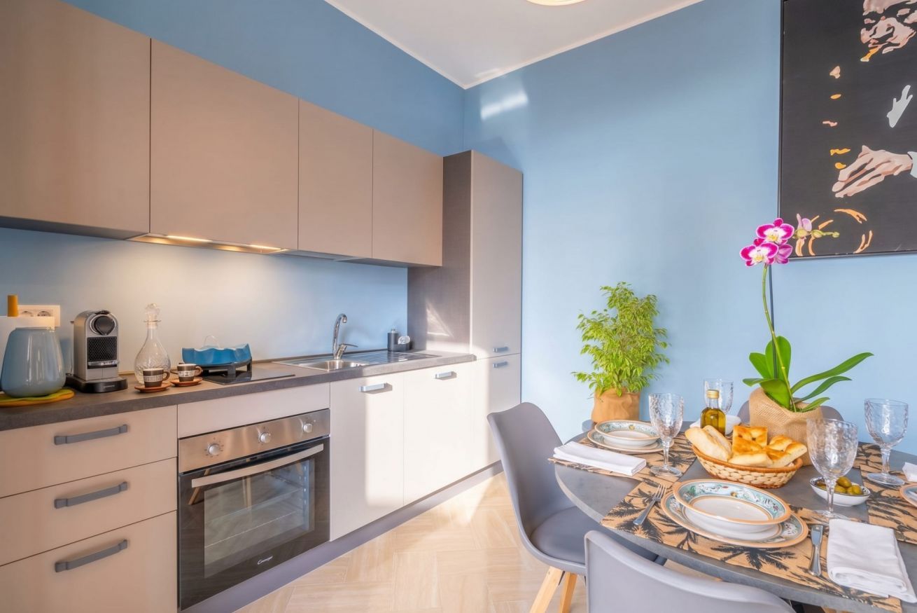 Una cocina moderna con horno empotrado, una mesa de comedor dispuesta con platos, vasos y un centro de mesa.