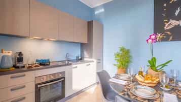 Una cocina moderna con horno empotrado, una mesa de comedor dispuesta con platos, vasos y un centro de mesa.