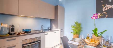 A modern kitchen with a built-in oven, a dining table set with plates, glasses, and a centerpiece.