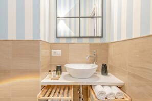 A modern bathroom with a large vessel sink, a mirror, and a towel rack.