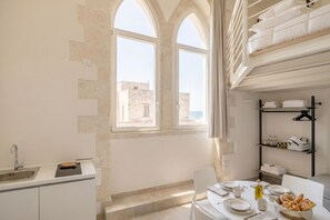 Une cuisine moderne équipée d’un four encastré, d’un évier et d’un coin repas avec une table dressée pour deux personnes.