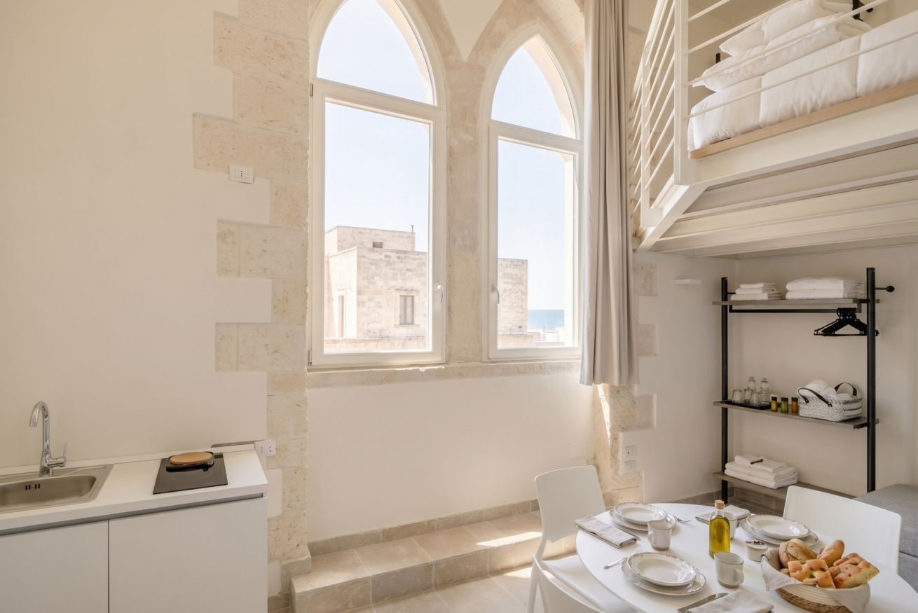 Una cucina moderna con forno a incasso, lavello e zona pranzo con tavolo apparecchiato per due.