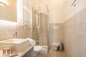 Une salle de bain avec une douche à parois de verre, un lavabo avec des articles de toilette et des toilettes.
