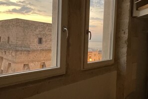 A window with a view of a building with a stone facade and a door. - Palazzo della Torre 203 - Panoramic View (Bari)