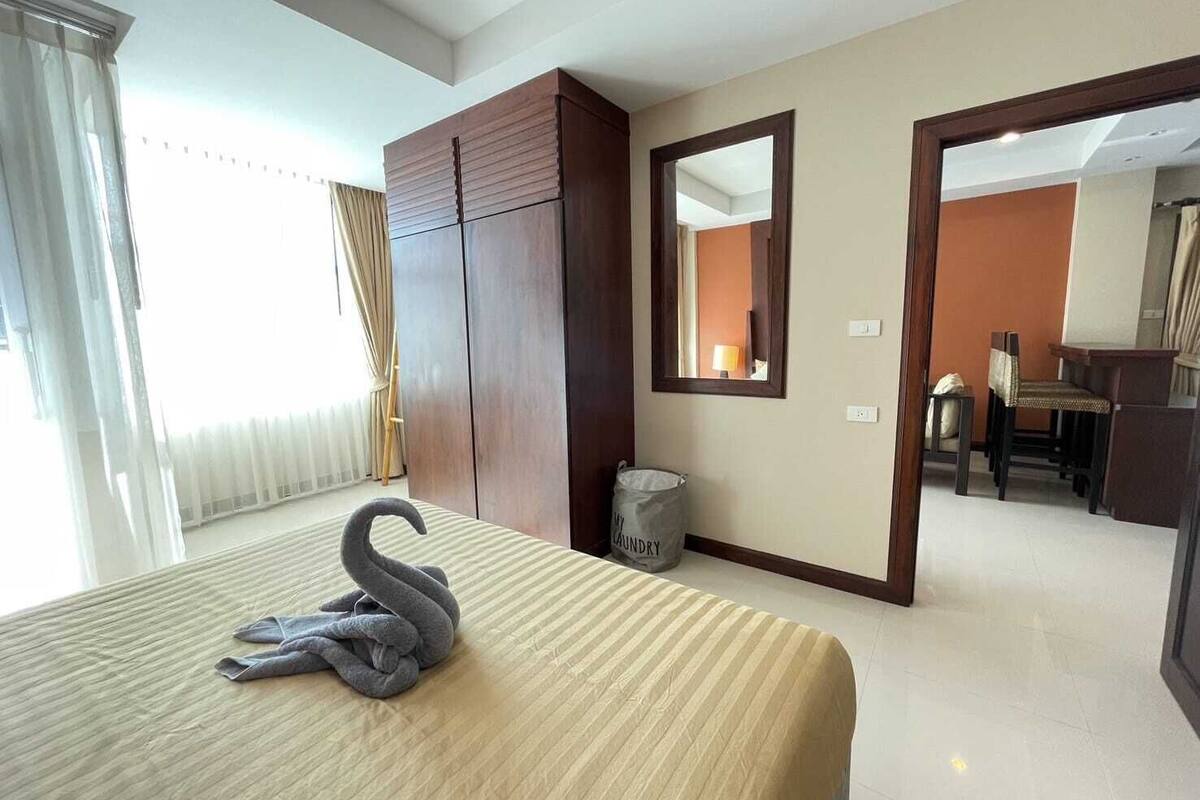 A hotel room with a bed, a wardrobe, a mirror, a desk, and a chair.