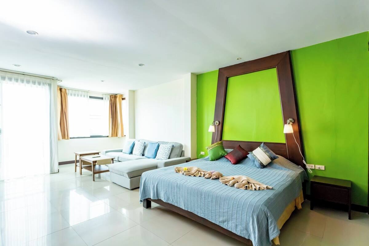 A modern hotel room with a large bed, a sofa, and a small table.