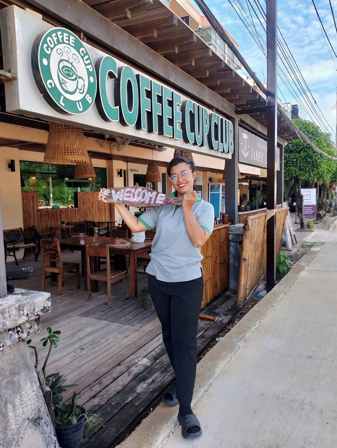 A coffee shop named "Coffee Cup Club" with outdoor seating and a wooden deck.