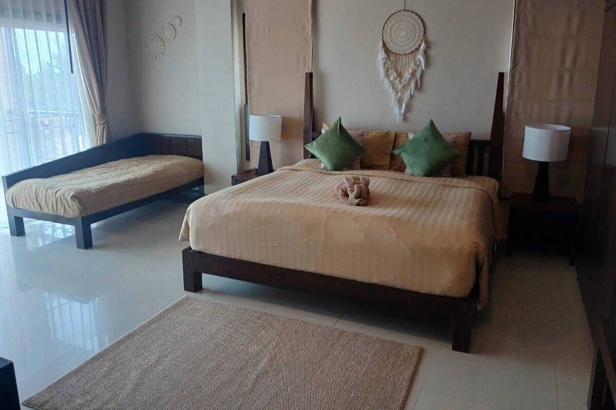 A bedroom with a large bed, two bedside tables with lamps, a dreamcatcher, and a small rug.