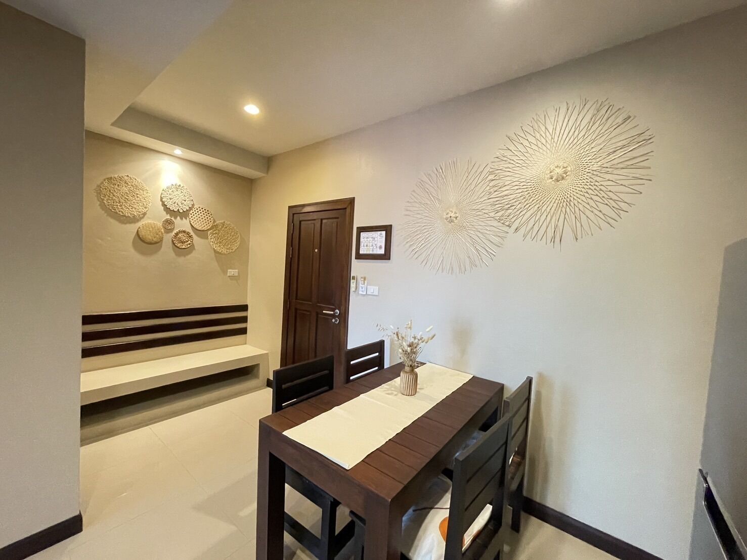 A dining area with a wooden table, chairs, a bench, and a decorative wall piece.