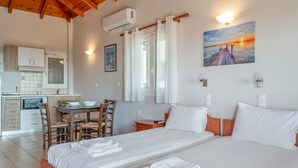 Ein Hotelzimmer mit Bett, Schreibtisch, Stuhl, einem kleinen Tisch und einer Küchenzeile.
