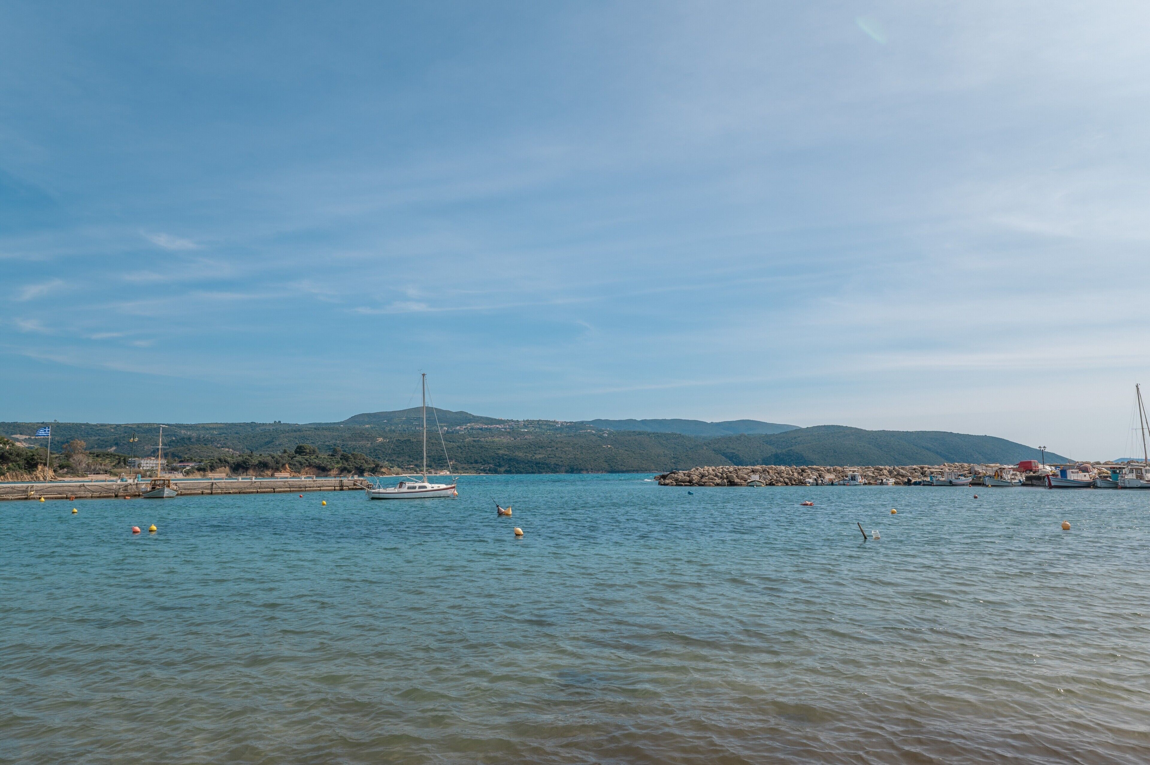 Una riva tranquilla con barche, un molo e colline all'orizzonte.