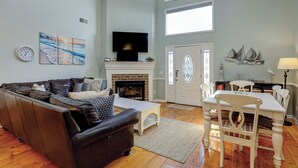 Una sala de estar con chimenea, televisor y comedor con sillas y mesa.