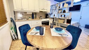 Un coin repas avec une table ronde en bois, deux chaises bleues et un chemin de table bleu.