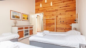 A hotel room with wooden panel walls, a bed, a vanity with a mirror, and two framed pictures on the wall.