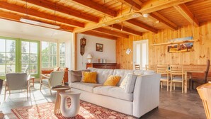 A cozy living room with a sofa, chairs, a dining table, and a red patterned rug.