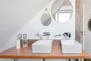 Ein Badezimmer mit zwei Waschbecken, einem Spiegel und einem Handtuchspender.