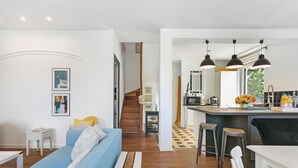 A modern interior with a blue sofa, wooden flooring, a kitchen island, and pendant lighting.