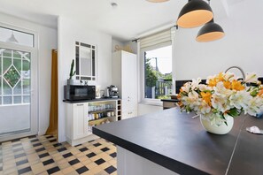A modern kitchen with a black countertop, white cabinets, and a window with a view of greenery. - Holiday Home 'Villa GoALL'O' 400m from the Port of Saint-Quay-Portrieux (ETABLES SUR MER)