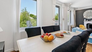 A dining area with a table, chairs, a fruit bowl, and a clock on the wall.
