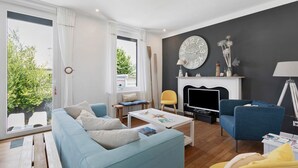 A living room with a sofa, armchairs, a coffee table, a fireplace, and a TV.