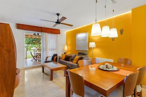 Una sala de estar moderna con comedor, ventilador de techo y vistas del patio exterior.