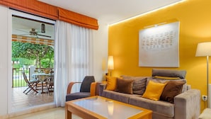 Een woonkamer met een bank, een bijzettafeltje, een lamp en uitzicht op een terras.
