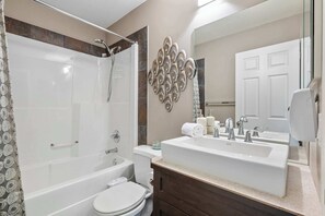 Een badkamer met douche, toilet en wastafel.