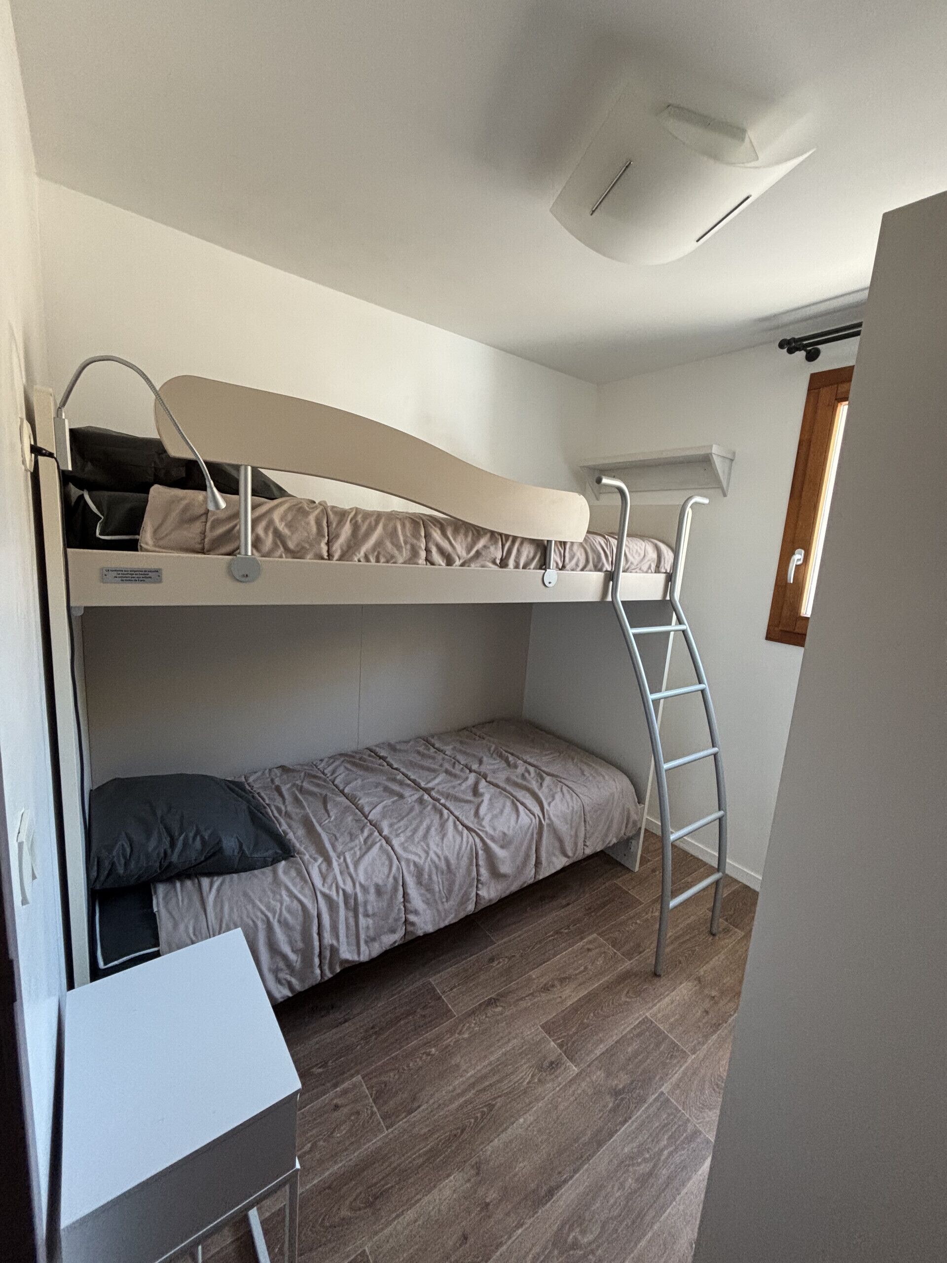 A bunk bed room with a desk and a ladder.