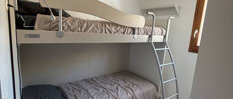 A bunk bed room with a desk and a ladder.