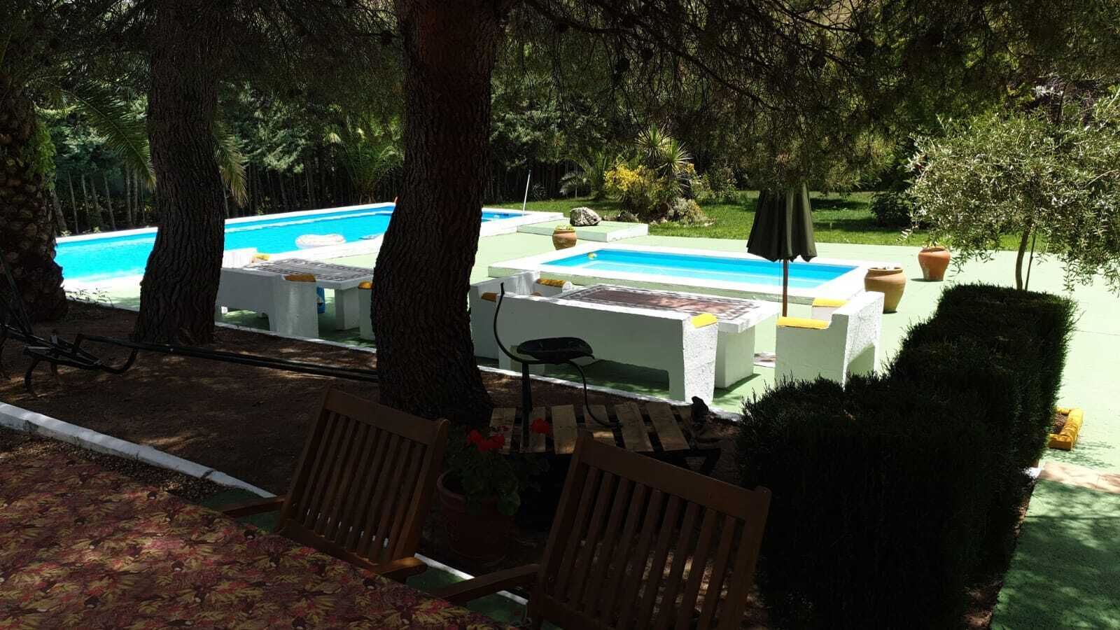 Un espace piscine comprenant un transat, une table et un banc.