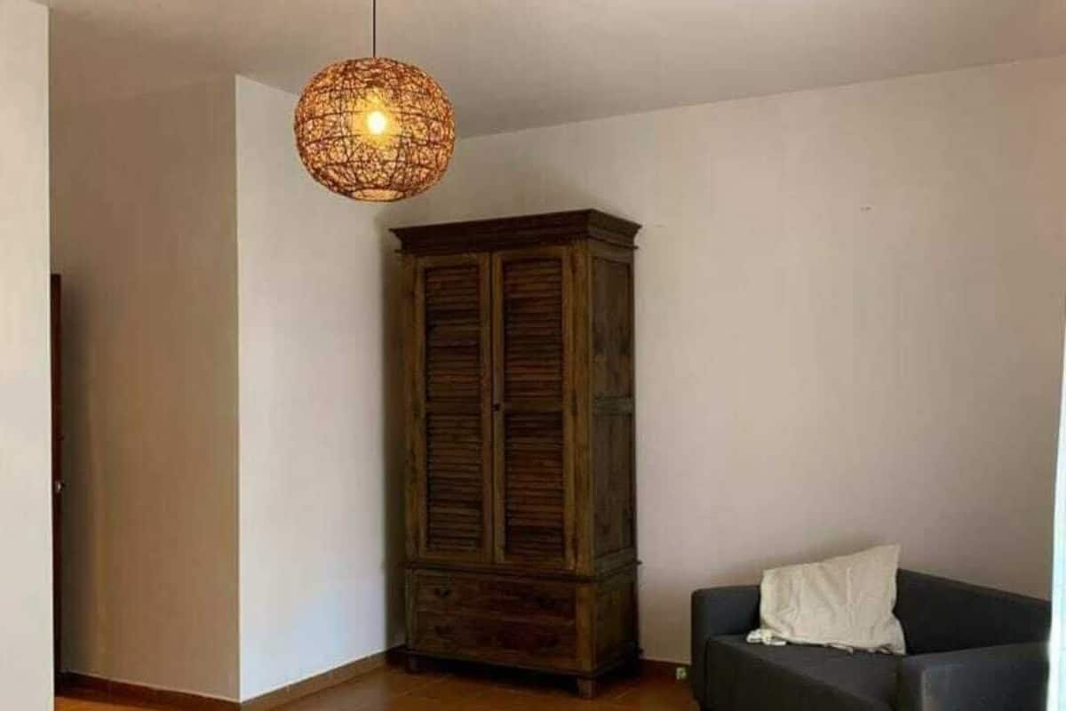 A living room with a wooden cabinet, a sofa, and a hanging light fixture.